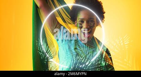 Fan afro-américain avec drapeau brésilien et peinture de visage par des plantes et un cercle illuminés Banque D'Images