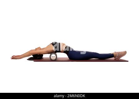 Posez la jeune femme couchée sur un tapis avec le rouleau derrière pendant l'entraînement Banque D'Images