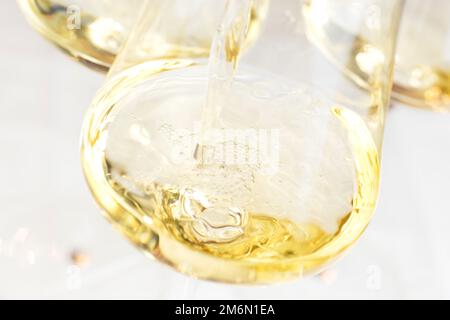 Verser du vin blanc dans un verre avec un fond clair - attention sélective sur les bulles Banque D'Images