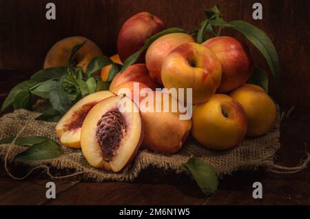 Nectarines sur un tissu épais sur un fond en bois sombre dans un style rustique Banque D'Images