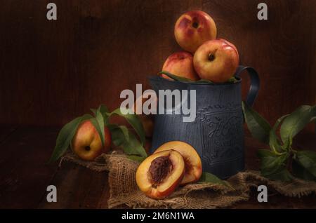 Nectarines dans une carafe en métal sur fond de bois sombre dans un style rustique Banque D'Images