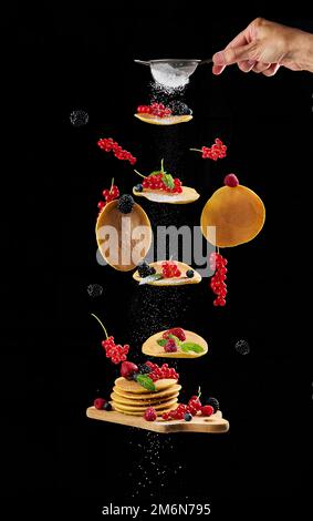 Crêpes rondes, fruits variés sur fond noir Banque D'Images