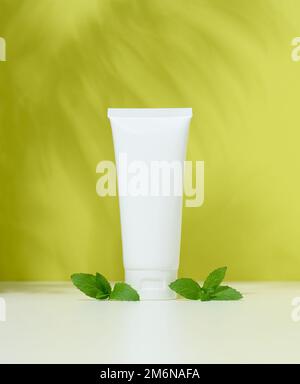 Vider les tubes en plastique blanc pour les cosmétiques sur fond vert. Emballage pour crème, gel Banque D'Images