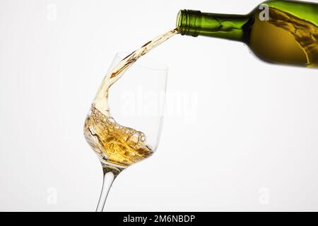 Vin blanc versé à partir d'une bouteille verte, gros plan sur blanc isolé. Banque D'Images
