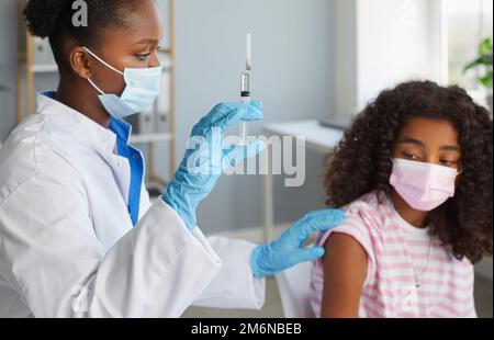 Le médecin donne une injection de vaccin à l'adolescence fille dans l'épaule dans le concept de vaccination de clinique. Banque D'Images