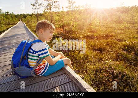 Enfant assis sur le broadwalk en bois et regardant la tourbière. Banque D'Images