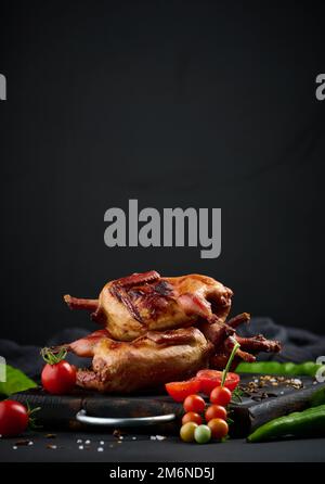 La friture des carcasses de cailles repose sur une planche en bois avec des légumes, une table noire Banque D'Images