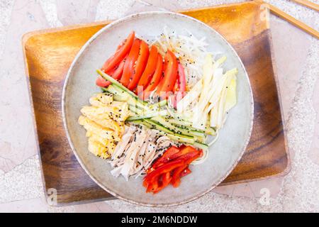 Hiyashi Chuka est une nouilles de ramen froid japonaise mélangée avec une vinaigrette maison et recouverte d'oeuf, de crabe imitation, de jambon, de concombre et de tomate. Banque D'Images