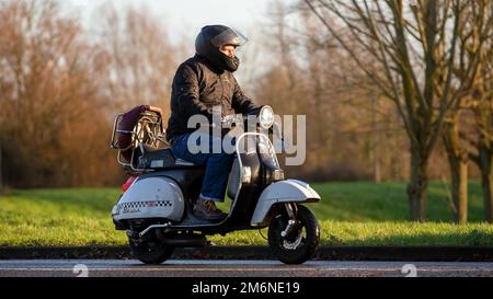 Homme à cheval sur un Vespa Banque D'Images