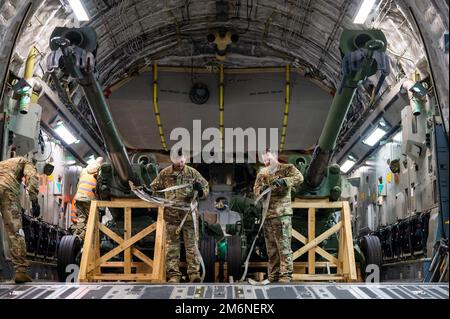 Le sergent d'état-major Evan Minca, le capitaine de pont du 517th escadron de transport aérien, et le capitaine Andrew Miller-Bissell, tous deux de la base interarmées Elmendorf AK., se préparent à décharger M777 obusiers d'un C-17 Globemaster III en Europe de l'est, au 2 mai 2022. L'assistance de sécurité que les États-Unis fournissent à l'Ukraine permet un succès critique sur le champ de bataille contre la force russe d'invasion. Banque D'Images