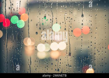 gouttes de pluie sur la fenêtre et lumières de rue arrière-plan la nuit Banque D'Images