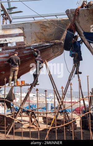 Bateau dans un quai sec pour réparation, avec des travailleurs sur des escabeaux Banque D'Images