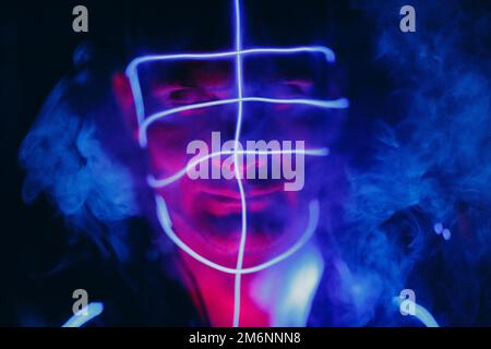 Portrait d'un homme avec des lignes lumineuses au néon sur son visage.Concept de cyber-punk et de réalité virtuelle. Banque D'Images