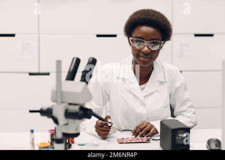 Scientifique afro-américaine femme travaillant en laboratoire avec des instruments électroniques Banque D'Images