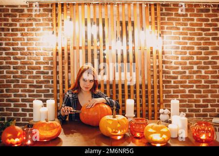 Jeune femme faisant la citrouille d'Halloween Jack-o-lanterne. Les mains de femmes coupantes des citrouilles avec un couteau. Banque D'Images