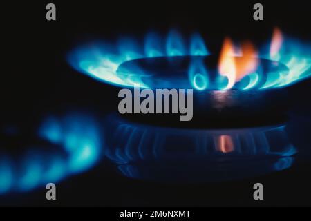 Flamme de gaz, cuisinière dessus cuisinière bleu orange feu dans l'obscurité, espace copie Banque D'Images