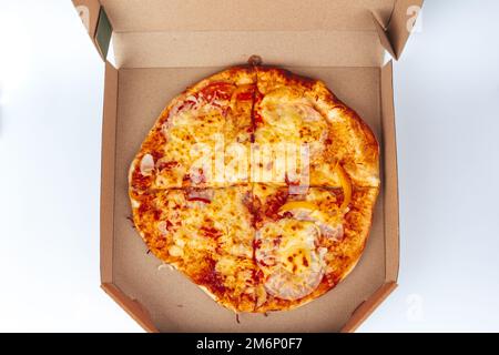 Pizza dans une boîte en carton isolée sur un fond blanc. Vue de dessus de l'emballage de pizza. Des plats délicieux, juteux et savoureux. En-cas rapide. Mauvaise restauration rapide Banque D'Images