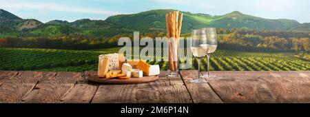 Deux verres de délicieux vin blanc avec hors-d'œuvre au fromage sur une table en bois. Belle vue sur le champ en été Banque D'Images