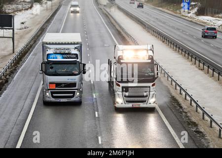 Le camion semi-remorque White Volvo FH MHL Trans prend le dessus d'un autre camion Volvo sur autoroute humide par un jour pluvieux de l'hiver. Salo, Finlande. 22 décembre 2022. Banque D'Images