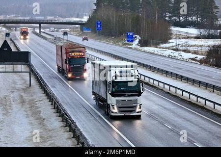 Les camions de transport de marchandises dans la circulation sur autoroute un après-midi d'hiver brumeux. Salo, Finlande. 22 décembre 2022. Banque D'Images