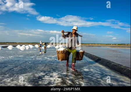 Un homme porte un panier de sel dans l'entrepôt de CAN Gio, Ho Chi Minh ville, Vietnam Banque D'Images
