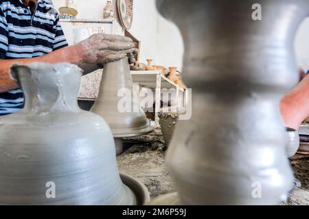 potier habile formant un navire d'argile grise dans une usine de poterie, Fès, Maroc, Afrique du Nord Banque D'Images