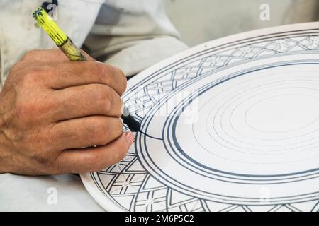 Artisans peignant et décorant des produits céramiques dans une usine de poterie à Fès, au Maroc, en Afrique du Nord Banque D'Images