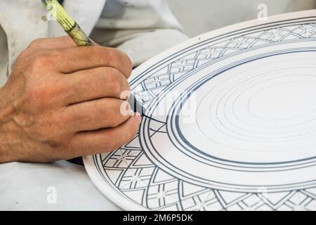 Artisans peignant et décorant des produits céramiques dans une usine de poterie à Fès, au Maroc, en Afrique du Nord Banque D'Images