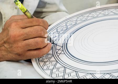 Artisans peignant et décorant des produits céramiques dans une usine de poterie à Fès, au Maroc, en Afrique du Nord Banque D'Images