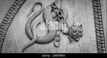 Symbole serpent de diable. Créature magique fantaisie sur une vieille porte, abbaye du 12th siècle en Italie. Banque D'Images