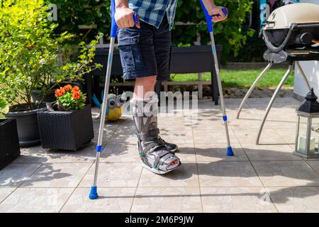 Jambe brisée avec orthese et béquilles après accident en Bavière en Allemagne. Banque D'Images