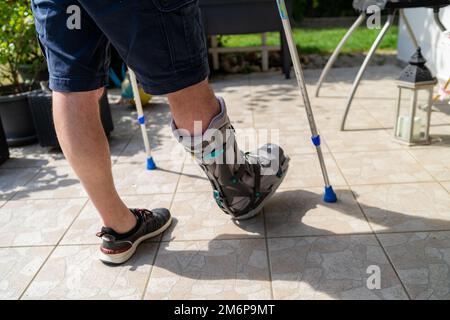 Jambe brisée avec orthese et béquilles après accident en Bavière en Allemagne. Banque D'Images