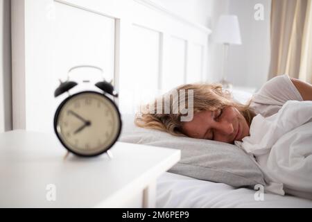 Réveil et femme dormant dans le lit qualité de sommeil Banque D'Images