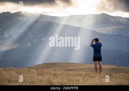 Homme prenant des photos de lumières célestes dans les montagnes Banque D'Images