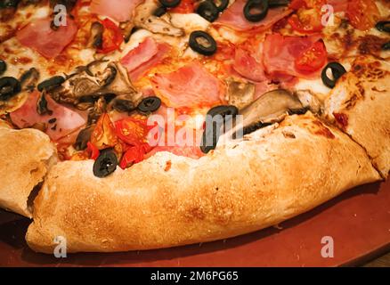 Pizza capriciosa avec croûte farcie au fromage dans la pizzeria, nourriture Banque D'Images