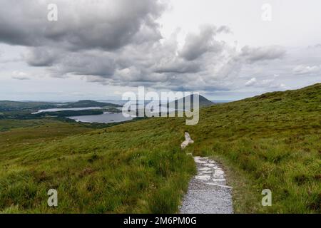 Le sentier de randonnée descendant du sommet de Diamond Hill dans le parc national du Connemara avec vue sur la côte et Kingstown PE Banque D'Images