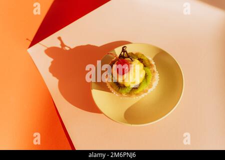 Délicieux petits gâteaux décorés de baies fraîches sur fond coloré Banque D'Images