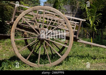 Un vieux chariot en bois avec de grandes roues dans l'arbre de fond de ferme Banque D'Images