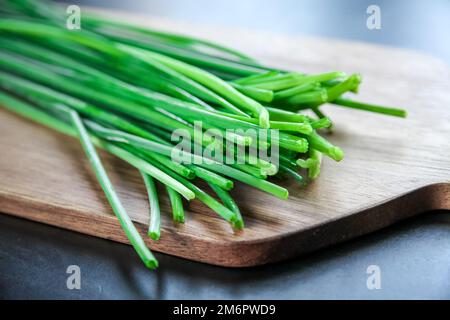 Bouquet de ciboulette sur une planche à découper en bois Banque D'Images