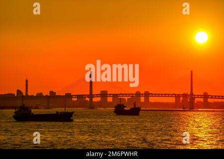 Silhouette de cargo et coucher de soleil sur les gratte-ciel de Yokohama Banque D'Images