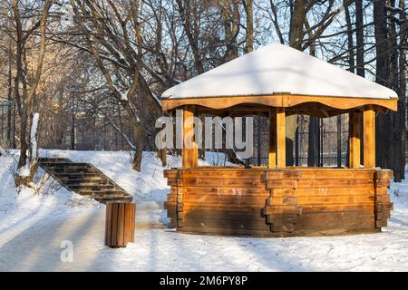 vieux belvédère en bois dans un parc d'hiver par une journée ensoleillée. belvédère en bois dans le parc. belvédère en bois recouvert de neige dans le parc. Banque D'Images