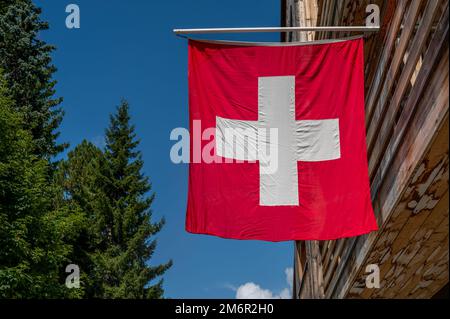 Drapeau suisse. Drapeau suisse suspendu sur le toit contre le ciel bleu. Un drapeau carré rouge avec une croix blanche au centre. Banque D'Images