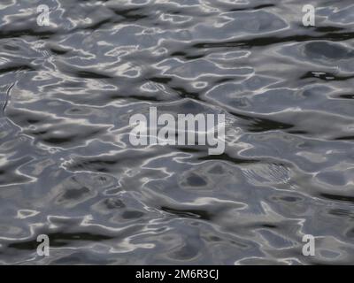 La texture de l'eau avec la lumière du soleil reflétant l'apparence du métal liquide Banque D'Images