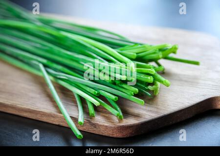 Bouquet de ciboulette sur une planche à découper en bois Banque D'Images