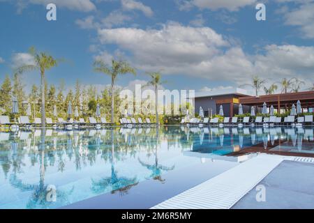 Magnifique parasol de luxe et chaise autour de la piscine extérieure dans l'hôtel et le complexe avec le cocotier sur ciel bleu Banque D'Images