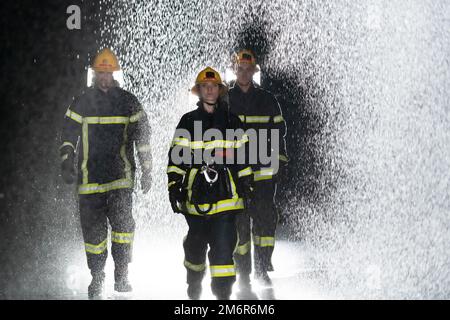 Portrait d'un groupe de pompiers debout et marchant courageux et optimiste avec une femme comme chef d'équipe. Banque D'Images