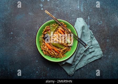Nouilles asiatiques sautées au poulet et aux légumes dans un bol vert vue du dessus Banque D'Images