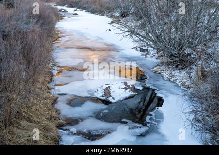 ruisseau gelé avec reflets du coucher du soleil - fourche nord de la rivière cache la poudre dans l'espace ouvert Eagle Nest dans le nord du Colorado Banque D'Images