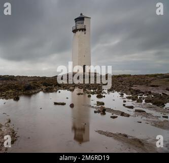 Le phare historique de la Southerness en Écosse avec des reflets dans les bassins de marée en premier plan Banque D'Images