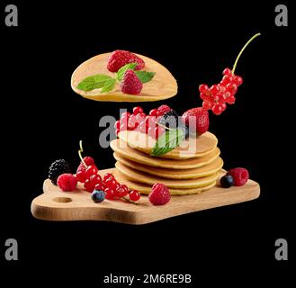 Crêpes cuites avec fruits frais sur un panneau de bois, fond noir Banque D'Images